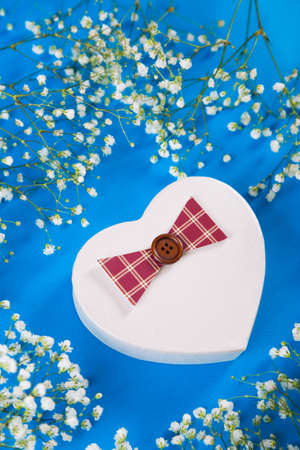 Gift box in shape of heart surrounded with white gypsophila flowers on blue background, high angle. Spring romantic present for women.の写真素材