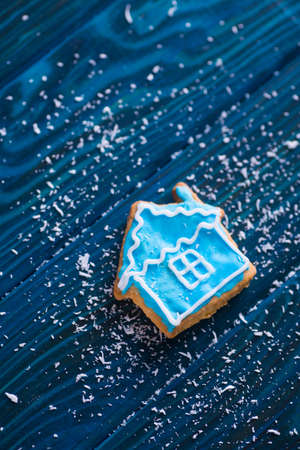 Closeup homemade Christmas glazed cookie in form of winter house on navy wooden table. New Year biscuit.の写真素材