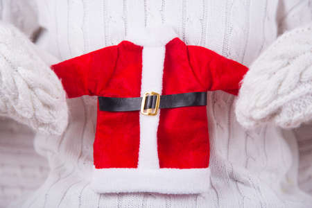 Hands in white knitted mittens holding toy Santa costume. Christmas banner. New Year card.の写真素材