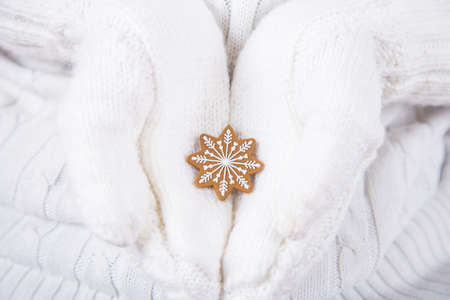 Hands in white knitted mittens holding little Christmas tree toy in form of snowflake. New Year decor.の写真素材