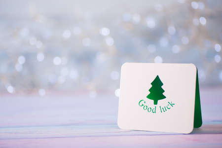 Christmas greeting card with green fir on light bokeh background. New Year gift with copy space.の写真素材