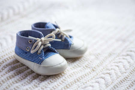 Cute baby boy blue sneakers on white knitted fabric. Concept of first shoes.の写真素材