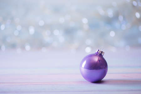 Purple Christmas ball on light bokeh background. New Year festive card with copy space.の写真素材