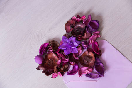 Heart made from purple dried flowers and petals in lilac envelope, floral composition flat lay, top view. Romantic card for Valentine Day.の写真素材