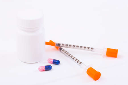 Insulin syringes, two capsules and plastic bottle on white background. Concept of choice of diabetes-lowering therapy.の写真素材