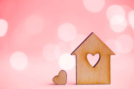 Wooden house with hole in form of heart with little heart on pink bokeh background. Concept of sweet home.の写真素材