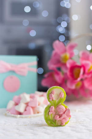 Decorative figure eight with beautiful bouquet of tender pink tulips and gift on light background with bokeh. Concept of Women's day gift. Spring romantic composition with copy spaceの写真素材