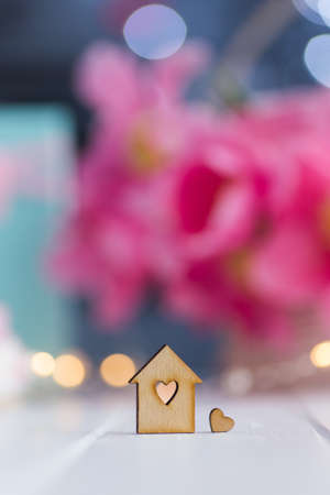 Closeup wooden house with hole in form of heart with beautiful bouquet of tender pink tulips on blurred background with bokeh. Spring romantic composition with copy spaceの写真素材
