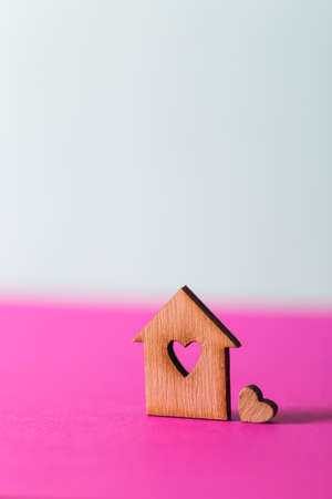 Closeup wooden house with hole in form of heart on vibrant two-colored background. Concept of sweet home, copy spaceの写真素材