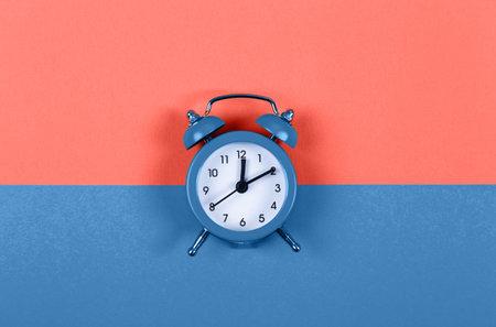 Cute little alarm clock in center on two colored background - Living Coral and Classic Blue. Color...