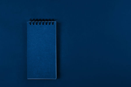 Blank page of a notebook on spiral on plain background, top view. Trendy banner with color of the...