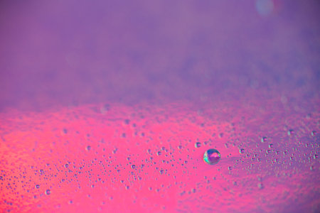 A lot of small drops of water on a colorful pastel holographic purple and pink background. Abstract...