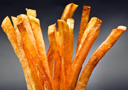 Well fried potato fries on dark background close up