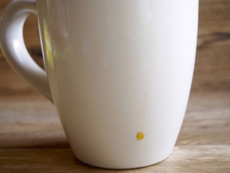 Foreground of a black coffee cup with a fallen dropの写真素材