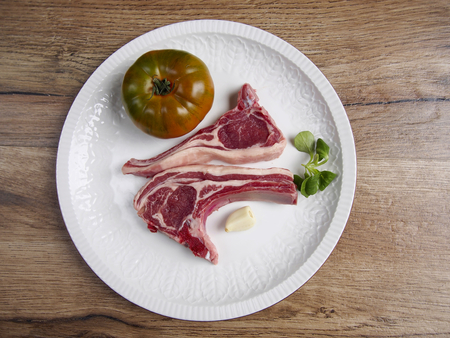 Two lamb chops with tomato and garlic in a plateの写真素材