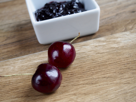 Cherry jam unfocused with two cherries on wood backgroundの写真素材