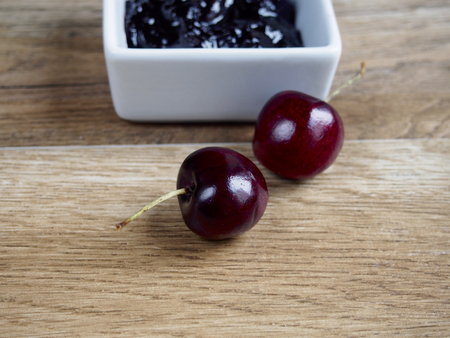 Cherry jam with two cherries on wood backgroundの写真素材