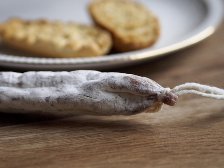 Fuet - Spanish sausage - on wood background with unfocused breadの写真素材