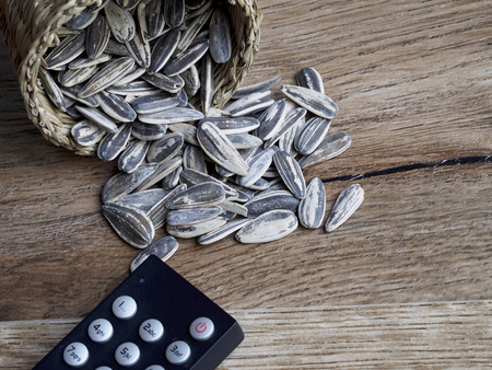 Sunflower seeds in wicker basket and remote control tvの写真素材