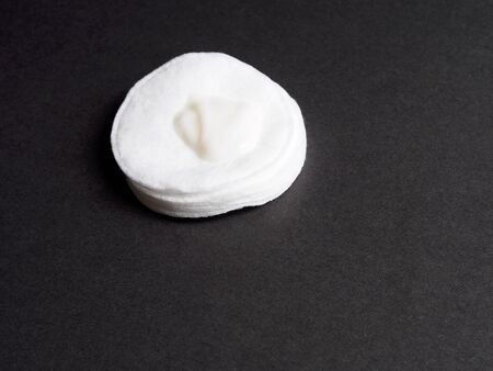Cotton disc with cream on black backgroundの写真素材