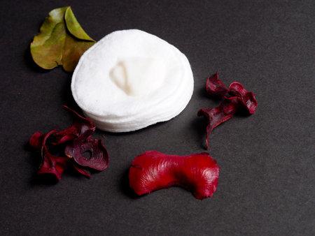Cotton disc with cream and dry flowers on black backgroundの写真素材