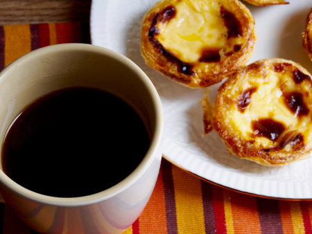 Custard tarts in a plate and a black coffee cup
