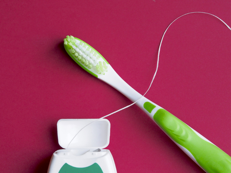 Dental floss and toothbrus on red backgroundの写真素材