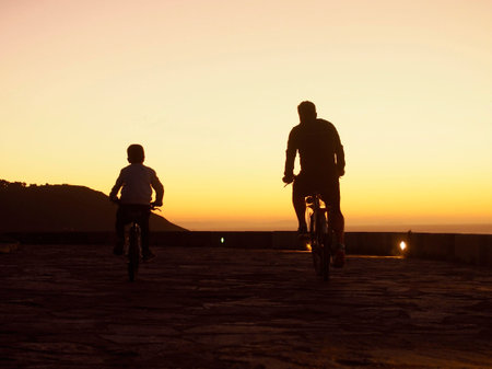 Father and son ridding bicycle in the sunsetの写真素材