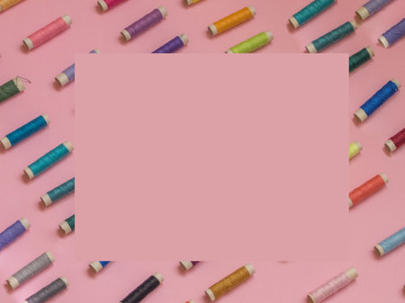 Thread spools pattern on pink background with copy space