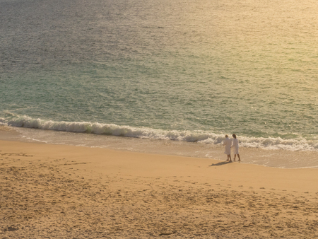 Couple walking on the beach with white bathrobeの写真素材