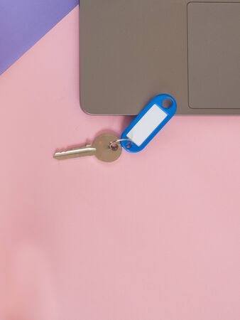 Computer and a metal key on pink background with copy spaceの写真素材