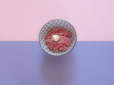 Minced beef meat in a bowl on pink and purple backgroundの写真素材