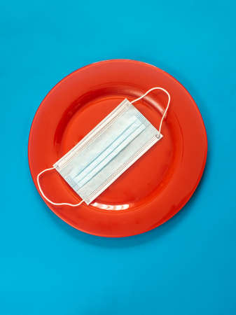 Red plate with mask on blue background - Cooking and eating in pandemic times conceptの写真素材