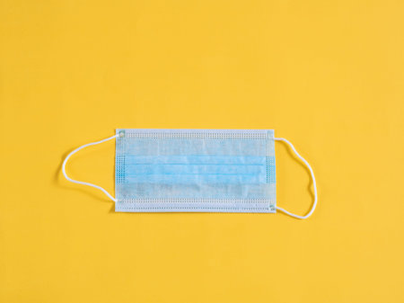 Surgical mask on yellow background