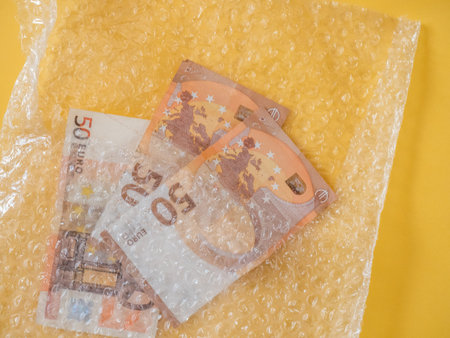 Banknote euros inside a plastic bubbles bag on yellow background - Protect your money concept