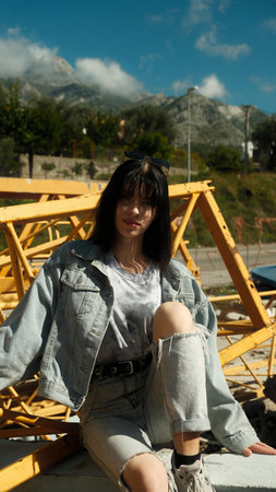 A teenage girl sits in an abandoned house against the background of metal structuresの写真素材