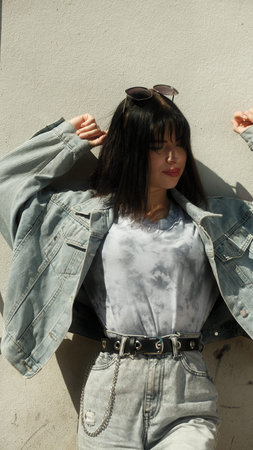 Teen girl in a denim jacket raised her hands and poses