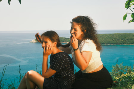 Mother braids her daughter's braids and looks at them. The sea in the backgroundÑ Cinematic imageの写真素材