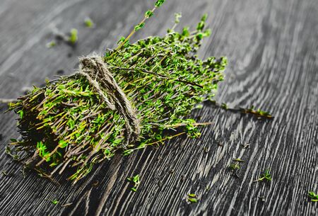 Bunch of thyme tied by a rope on a dark wood backgroundの写真素材
