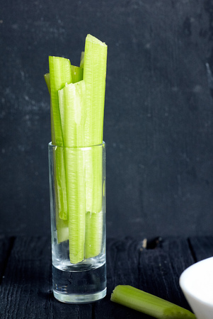Cutted celery sticks in small glass on black background. Snack for buffalo wingsの写真素材