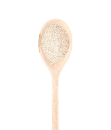 Instant dry yeast on wooden spoon isolated on white background. Yeast is a main ingredient of fresh bread dough, pizza dough and many other dough's.の写真素材
