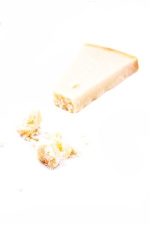 Pieces of parmigiano reggiano or parmesan cheese isolated on white. Parmesan is hard cheese uses in pasta dishes, soups, risottos and grated over salads.の写真素材