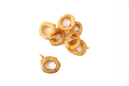 Stack of freshly made crispy Golden onion rings. A wonderful, flavorful snack for beer or another beverage. Fastfood appetizer from the deep fryer. Isolated on white background close up shot.の写真素材