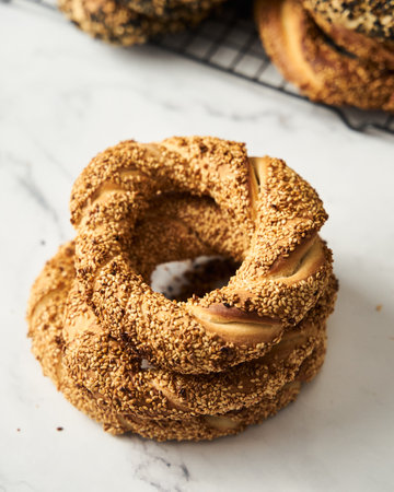 Close up of Turkish simit bread pretzels stack. Homemade Sesame bagel on white marble background.の写真素材
