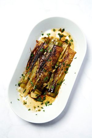 Leeks fried and poached in wine and butter sprinkled with finely chopped parsley. The perfect appetizer for a fishの写真素材