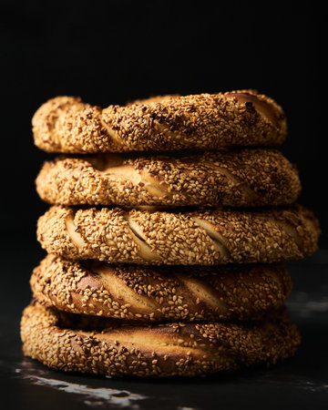 Close up ofTurkish simit bread pretzels stack. Homemade Sesame bagel on dark background. Low key, dark photoの写真素材