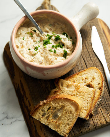 Sour cream, yogurt and caramelized onion spread dip in the bowl on wood board. bread pieces are near...