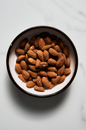 Roasted Almonds in the bowl on white marble kitchen countertop. Top viewの写真素材