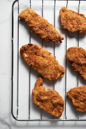 Close Up of Baked Chicken Schnitzel in breadcrumbs schnitzel on grid.の写真素材