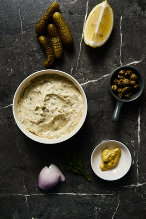 Classic Tartar Sauce with it ingredients on dark stone or marble background. Mayonnaise with dill and pickled cucumbers with lemon. Top view food photo. Flatlayの写真素材